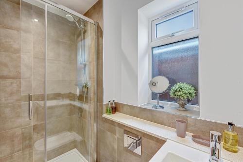 a bathroom with a shower and a sink and a window at St Martins 2 Bedroom Apartments in Ruislip By 360 Stays in Ruislip