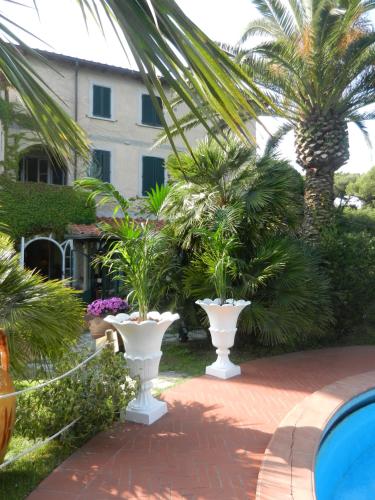 two large white vases with palm trees in front of a building at Hotel Villa Maremonti in Marina di Massa
