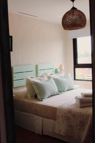 a bedroom with a bed with white pillows and a window at Posada de la Viuda in Punta Del Diablo