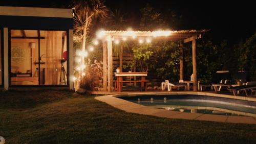 a backyard with a pool and a pergola at night at Posada de la Viuda in Punta Del Diablo
