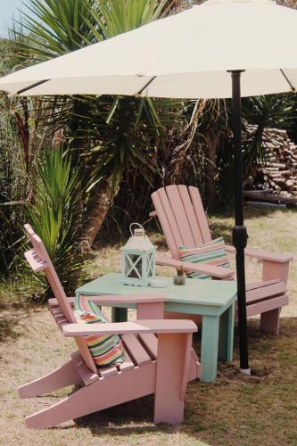 a table and two chairs under an umbrella at Posada de la Viuda in Punta Del Diablo