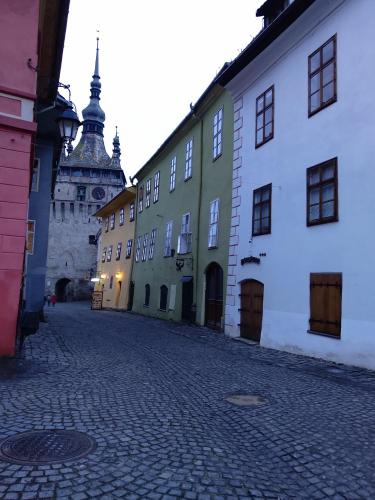 a cobblestone street with buildings and a castle at Horea 11 in Sighişoara