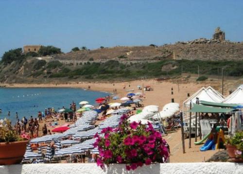 a beach with chairs and umbrellas and people on the beach at Bahari Beachfront Aparthotel Selinunte in Marinella di Selinunte