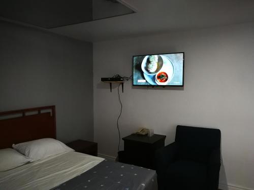 a bedroom with a bed and a tv on the wall at Motel Chez Nous in Laval