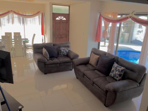 a living room with two couches and a television at Casa Playa Bahia Ballena de Osa in Uvita