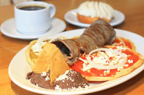a plate of breakfast food with sausage and sauce and a cup of coffee at Hotel Central in Veracruz