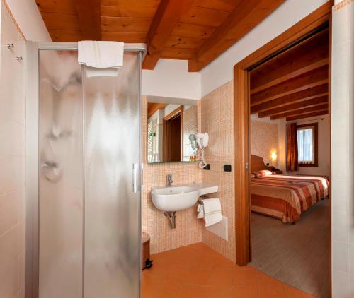 ein Bad mit einer Dusche, einem Waschbecken und einem Bett in der Unterkunft Albergo Antica Corte Marchesini in Campagna Lupia