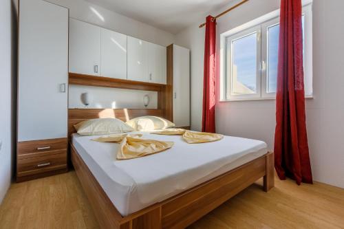 a bedroom with a bed with white sheets and a window at Apartments KULAS in Novi Vinodolski