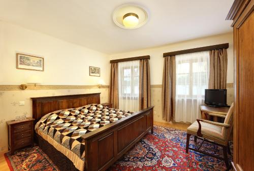 a bedroom with a bed and a desk and a television at Hotel Konvice in Český Krumlov