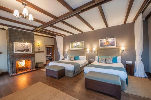 a large bedroom with two beds and a fireplace at The Retreat at Ngorongoro in Karatu