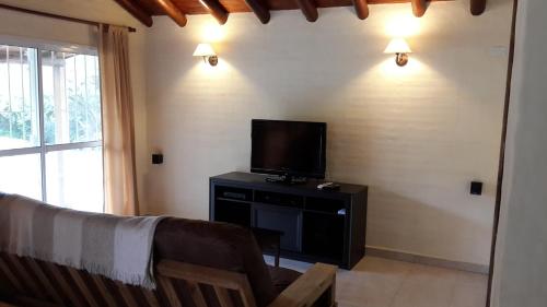 uma sala de estar com um sofá e uma televisão de ecrã plano em Cabanias El Aguaribay em San Javier