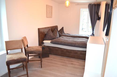 a bedroom with a bed and a chair and a window at Guesthouse Meitschi Thun - contactless self check-in in Thun