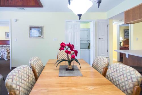 a dining room table with chairs and a vase of flowers at GetAways at Soundside Holiday Beach Resort in Pensacola Beach