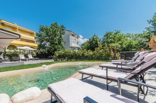 uma piscina com espreguiçadeiras ao lado de um edifício em Apartments Bego Spa & Wellness em Crikvenica