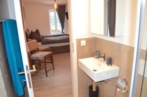 a bathroom with a sink and a mirror and a chair at Guesthouse Meitschi Thun - contactless self check-in in Thun