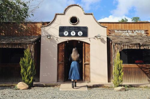 a woman in a blue dress walking into a building at Hotel Valle 13 Ruta del Vino in Valle de Guadalupe