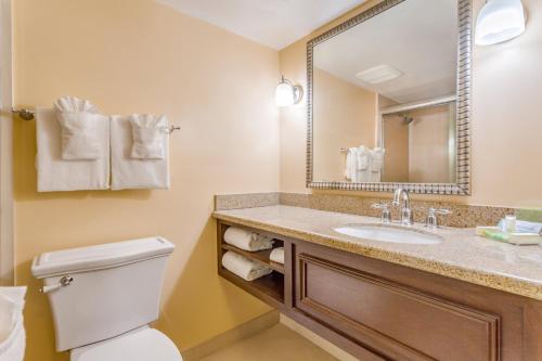 W łazience znajduje się umywalka, toaleta i lustro. w obiekcie Ocean Breeze Inn Vero Beach w mieście Vero Beach