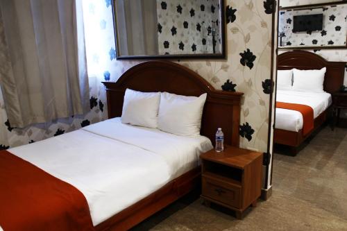 Un dormitorio con 2 camas y una mesa con una botella de agua. en El Regio en Monterrey