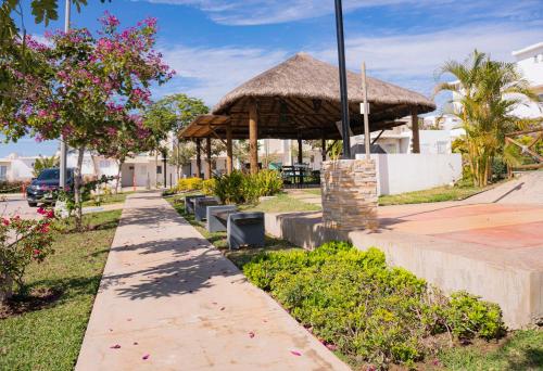 a pavilion with a thatched roof in a park at CASA EN PRIVADA FRENTE A LA PLAYA CON ALBERCA! in Mazatlán