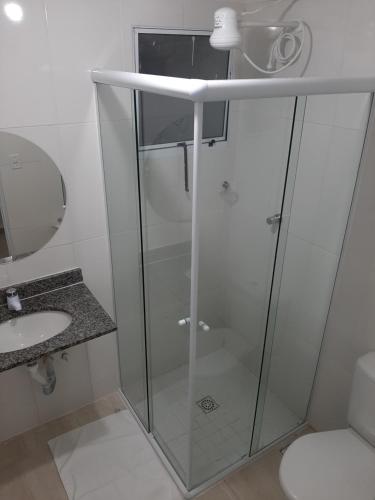 a glass shower in a bathroom with a sink at Pousada Praia Cia, Piscina, Centro, Estacionamento, WIFI, Saída até as 16h in Bertioga
