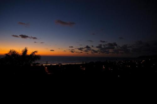 a sunset on the beach with the ocean and a city at Ocean View Happy Hill in Olón