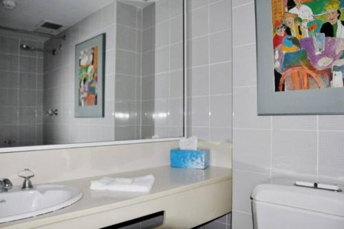 a bathroom with a sink and a toilet and a mirror at Accommodation Sydney: Hyde Park View 2 Bedroom 1 Bathroom Pet Friendly Apartment in Sydney