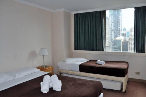 a hotel room with two beds and a window at Accommodation Sydney City Centre - 2 Bedroom Pet Friendly Apartment with Hyde Park View in Sydney