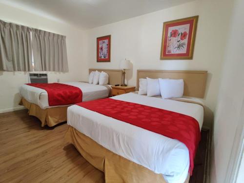 Habitación de hotel con 2 camas con sábanas rojas en Crown Inn, en Fort Lauderdale