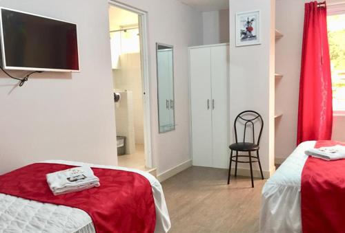 a room with two beds and a television and a chair at Casa Gaviota Dorada in Baños