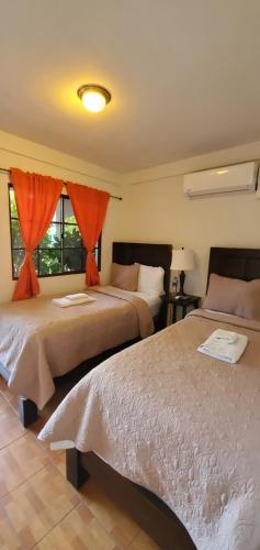 a bedroom with two beds with orange curtains at Hotel & Restaurant Fleur de Lis in Concepción de Ataco