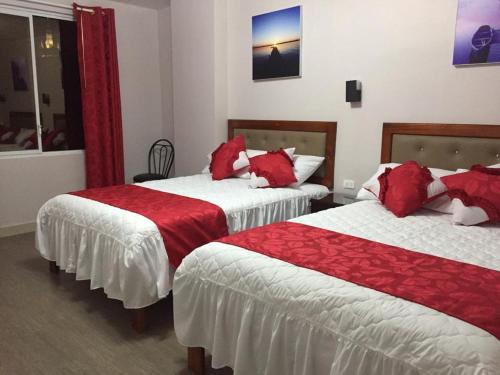 two beds in a hotel room with red pillows at Casa Gaviota Dorada in Baños