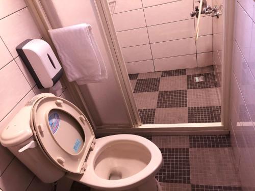 a bathroom with a toilet with the seat up at 金門后倉七號新古厝民宿 in Jinning