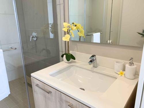 a bathroom sink with a vase of flowers on it at Menlyn Maine Residence Knysna in Pretoria