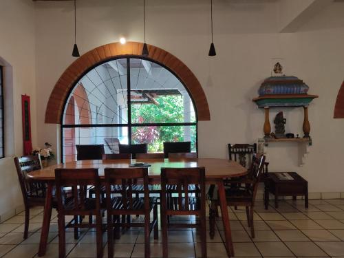 a dining room with a large wooden table and chairs at Gaia's Garden Guest House in Auroville