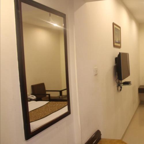 a mirror in a room with a bed and a chair at Regency Square Hotel in Gwalior