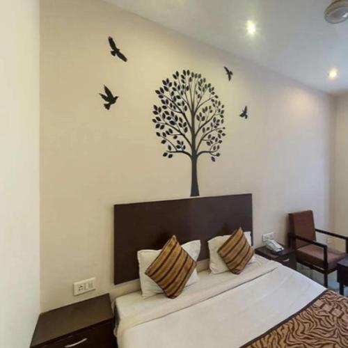 a bedroom with a tree and birds on the wall at Regency Square Hotel in Gwalior