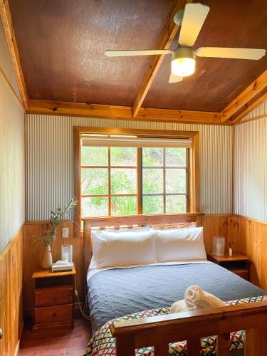a bedroom with a bed with a ceiling fan at Port Bayou Cottage in Port Campbell