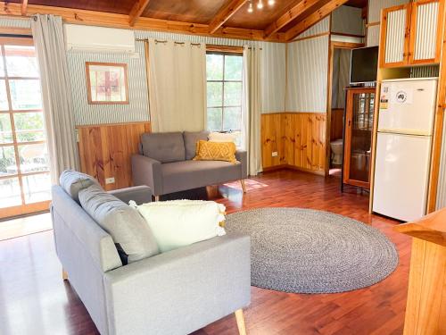 Una sala de estar con un sofá y un refrigerador. en Port Bayou Cottage, en Port Campbell