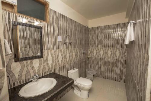 a bathroom with a sink and a toilet and a mirror at Hotel Nirmal Chhaya in Manāli