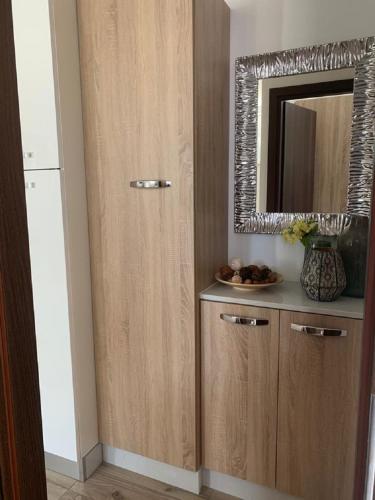 a bathroom with a wooden cabinet with a mirror at La Dolce Vita Apartments Unit 2 in Posedarje