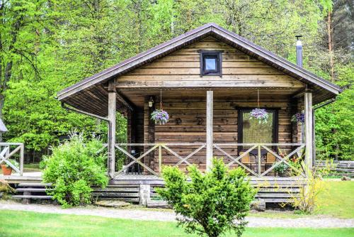 a log cabin with a porch and flowers on it at Sodyba Duburiai in Ukmergė