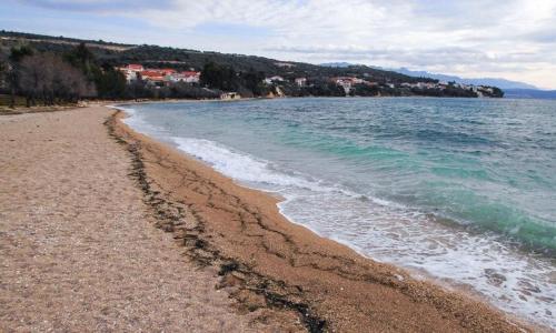 a sandy beach with the ocean and buildings in the background at La Dolce Vita Apartments Unit 2 in Posedarje