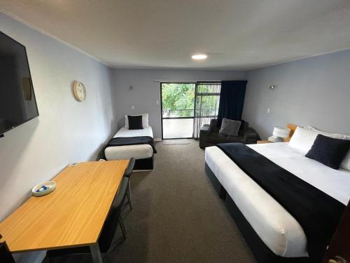 a hotel room with a bed and a table and a couch at Hacienda Motor Lodge in Palmerston North