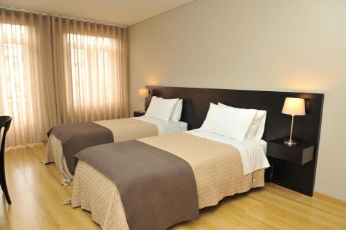 una habitación de hotel con 2 camas y una lámpara en Pensão Santo António, en Vila Nova de Famalicão