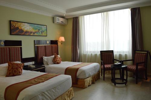 a hotel room with two beds and a chair at Tiffany Diamond Hotels - Mtwara in Mtwara