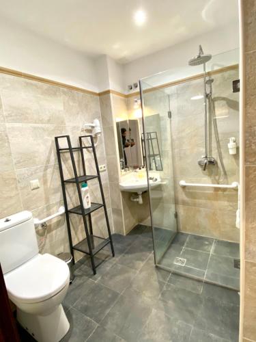 a bathroom with a toilet and a glass shower at Apartamentos Turísticos Espinel Free Parking in Ronda