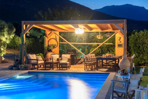 a patio with a table and chairs next to a swimming pool at Villa Odyssia in Agios Nikolaos