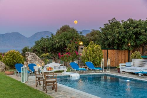 a backyard with a pool with chairs and a table at Villa Odyssia in Agios Nikolaos