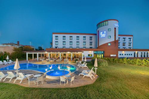 ein Hotel mit einem Pool und Stühlen sowie einem Gebäude in der Unterkunft Lu' Hotel Carbonia in Carbonia