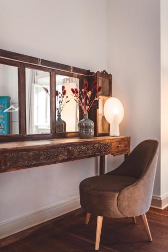 a chair sitting in front of a desk with a mirror at Hotel Villa Emden in Brissago